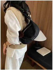 Schwarze Retro-Achseltasche im Dumpling-Stil, kombiniert mit einer beigen Strickweste