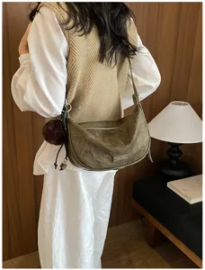 Detailansicht einer grünen Vintage-Hobo-Tasche mit einem dunkelbraunen Bommel-Anhänger