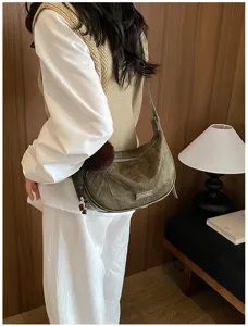 Modell mit olivgrüner Vintage-Halbmond-Schultertasche in Lifestyle-Umgebung