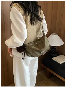 Retro-Schultertasche in Olivgrün mit Struktur am Model präsentiert