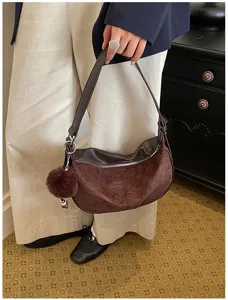 Braune Retro-Hobotasche im Dumpling-Stil getragen von einer Person im Büro-Outfit
