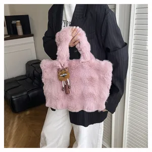 Detailansicht einer weichen, rosa Plüschtasche mit einem süßen, pelzigen Puppen-Anhänger.