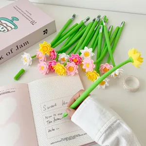 Close-up of a hand writing with a green silicone lotus flower gel pen in a notebook.