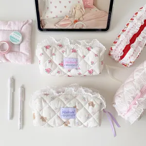 Collection of cream-colored quilted pencil cases with floral and bear prints and lace trim