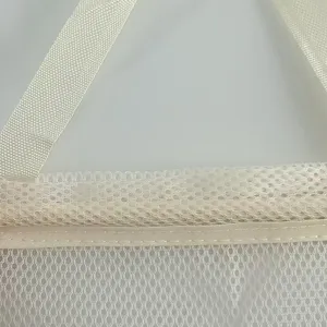 White mesh hanging storage bag detail shot, breathable material for kitchen home organization.