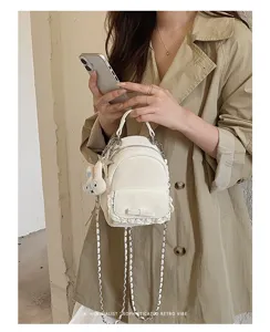 Detalle de una mini mochila blanca con delicado encaje y un lazo de cinta decorativo