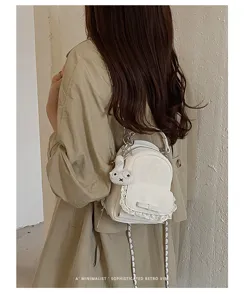 Vista detallada de una mini mochila blanca con encaje y lazo llevada por una modelo