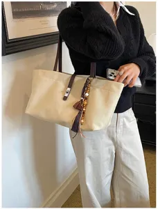 Bolso tote de lona literario con correas de cuero y borla bohemia usado por modelo