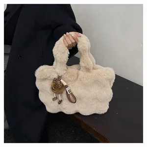 Nahaufnahme einer weichen flauschigen cremefarbenen Plüschtasche mit Leoparden-Anhänger