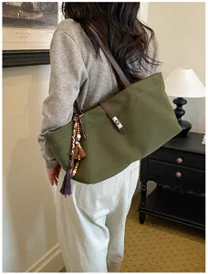 Bolso tote de lona verde con correas de cuero marrón y borla decorativa colgante