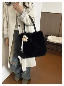 Detailansicht einer weichen schwarzen Kunstfelltasche mit geflochtenen Griffen am Modell