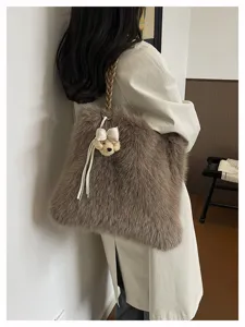 Nahaufnahme einer flauschigen Kunstpelztasche mit Bärenanhänger und geflochtenem Riemen