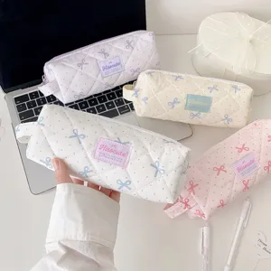 Gros plan de trousses à crayons matelassées à pois et nœuds aux couleurs pastel