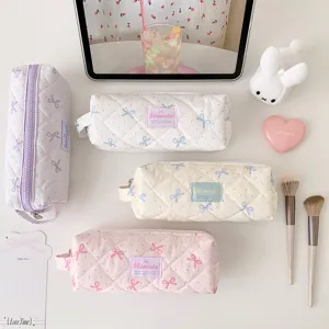 Collection de trousses matelassées à nœuds et pois dans des tons pastel présentées ensemble.