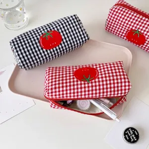 Detailed macro shot of red and black gingham pencil cases featuring a cute embroidered tomato patch