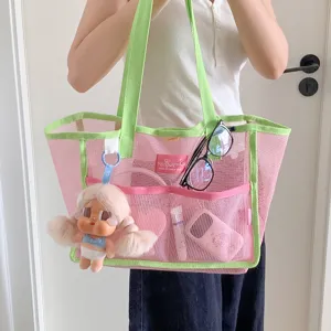 Bolso tote de malla rosa y verde llevado por una persona en un entorno de estilo de vida