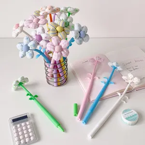 Colorful fabric flower gel pens displayed with cute stationery on a white desktop setup