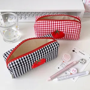 Detail macro view of cute checkered tomato pencil case with vibrant red zipper on desk.