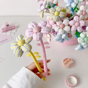 Close-up of cute fabric flower pens with soft pastel colors and leaf details