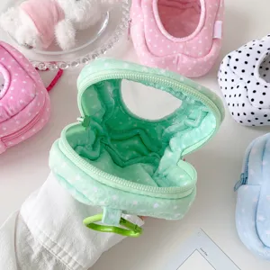 Close-up of mint green plush doll storage bag with polka dot lining and zipper