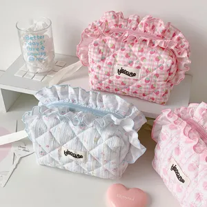 Vista dettagliata di pochette trapuntate con motivo a fragole ed eleganti bordi in pizzo