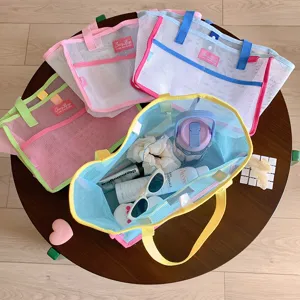 Grandes bolsos de malla llenos de artículos de playa como gafas de sol y botellas