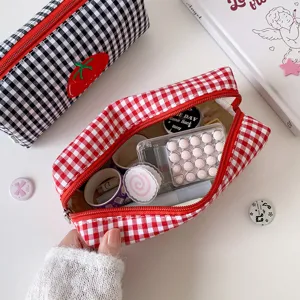 Close-up detail of red plaid pencil case with tomato embroidery showing interior stationery