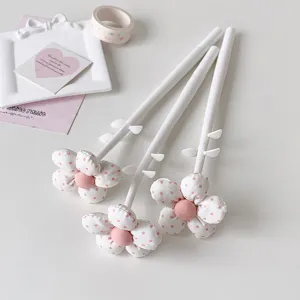 Close-up of three elegant fabric flower-topped gel pens with pink polka dot petals