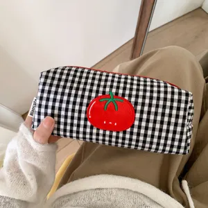 Detailed close-up of a black and white checkered canvas pencil case with a red tomato patch