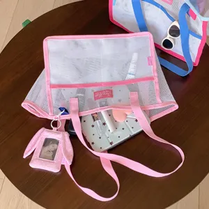 Vista detallada de un bolso de malla rosa con accesorios sobre una mesa de madera