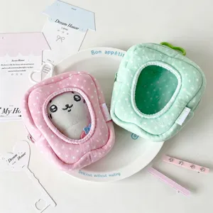 Detail view of tooth-shaped plush doll display pouches in pink and mint green colors.