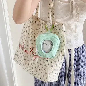 Mint green plush display pouch for dolls shown as a charm on a floral tote bag