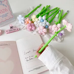 Detail shot of a hand writing in a notebook using a cute fabric flower pen topper.