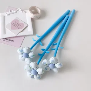 Close-up of blue pens featuring fabric flower toppers and creative stationery accessories