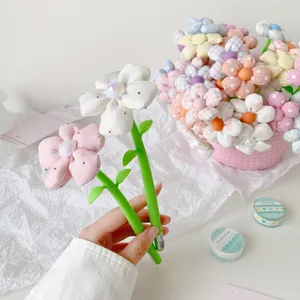 Close-up of hand holding cute fabric flower gel pens with pearlescent center and rhinestones