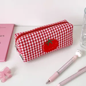 Detail view of a cute red and white checkered pencil case with a tomato patch embroidery.