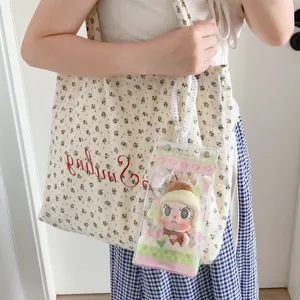 Close-up of a transparent PVC doll display bag attached to a floral tote bag