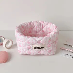 Close-up detail of cute pink quilted fabric storage basket with heart and bow patterns