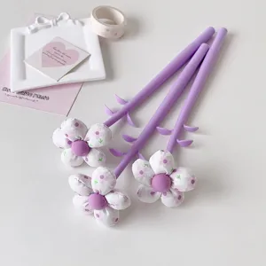 Detailed view of three purple fabric flower-topped gift pens with petal decorations