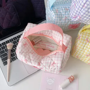 Gewatteerde ruitjes make-up tas met strikpatroon en cosmetica die binnenin getoond worden