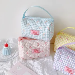 Een collectie schattige gewatteerde make-uptassen met ruitpatroon, roze strikjes en handvatten