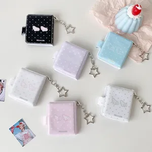 Vista detallada de mini álbumes de fotos pastel con llaveros de estrella y alas
