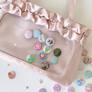 Close-up of cute 25mm mini button badges displayed in a pink ruffled ITA bag window