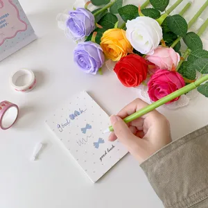 Close-up detail of a hand writing on a card with a creative green rose-shaped ballpoint pen