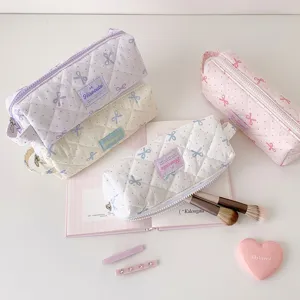 Plusieurs trousses matelassées avec motifs de nœuds et pois dans des tons pastel doux