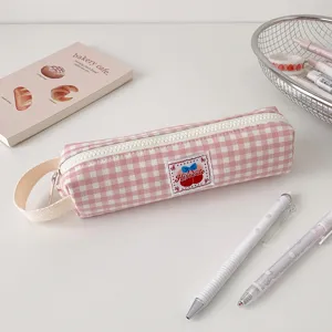 Dettaglio dell'astuccio a quadretti rosa con toppa a forma di ciliegia e cerniera color crema