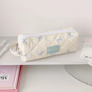Détail d'une trousse en tissu matelassé avec motif nœud bleu et étiquette Hisocute