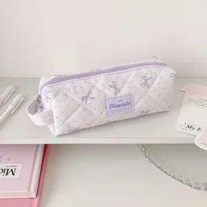 Vue détaillée d'une trousse matelassée violette à motifs de nœuds avec étiquette Hisocute