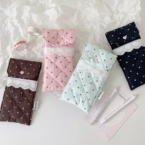 Detail of cute quilted polka dot pouches with elegant lace trim and heart buttons.