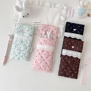 Close-up of quilted pencil pouches featuring lace trim, polka dots, and heart-shaped buttons